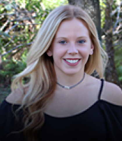 Woman smiling at camera outdoors with green foliage background, professional headshot style portrait.
