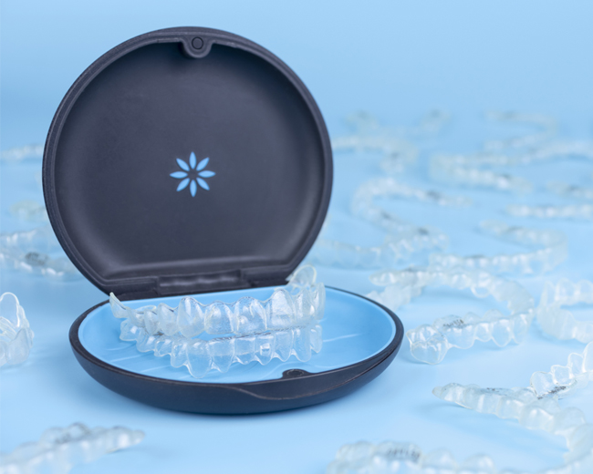 Open orthodontic retainer case with clear aligner inside on blue snowflake background