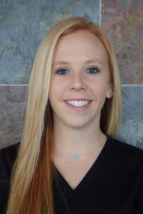 Young woman with long reddish-blonde hair smiling at camera in professional portrait setting.
