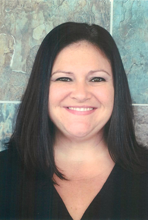 Professional headshot of a smiling woman with long dark hair against a textured blue-green background.