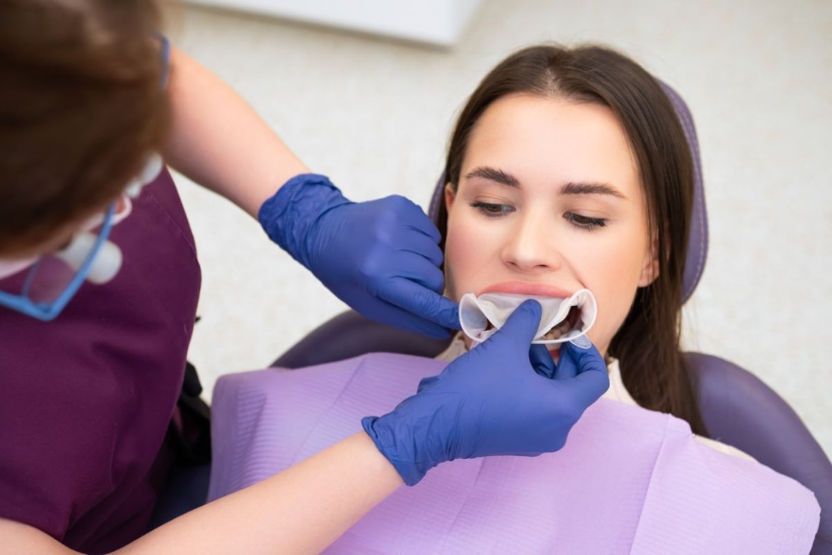 Dental professional examining patient's teeth during orthodontic consultation in clinical setting.